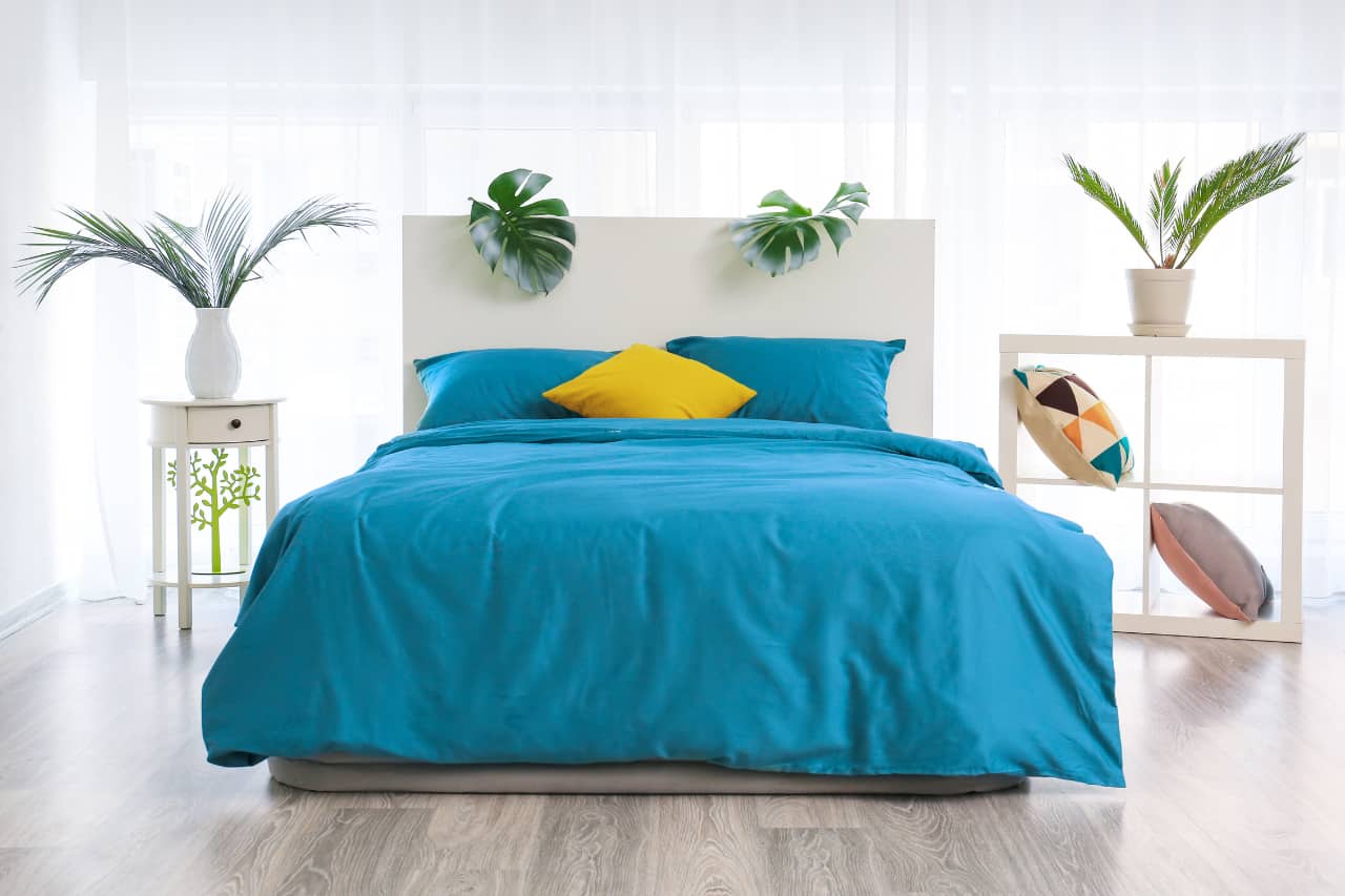Bold colors combine with touches of greenery make a vibrant tropical bedroom